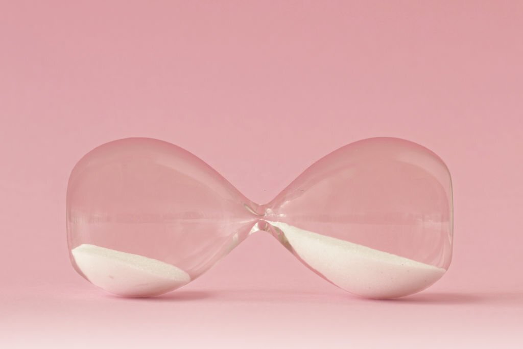 Hourglass lying on pink background
